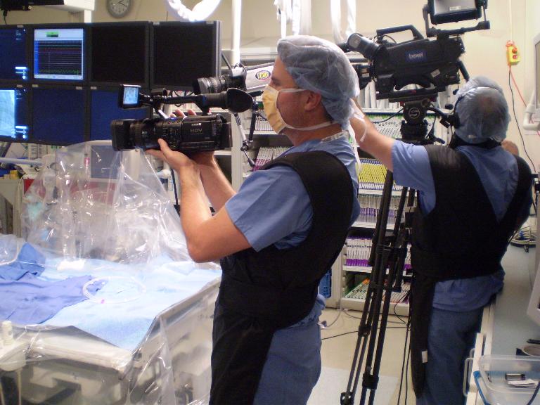 Medical cameraman Paul Skomal and another videographer videotape in operating room.