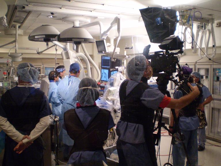 Wide view of medical videographer videotaping in operating room.